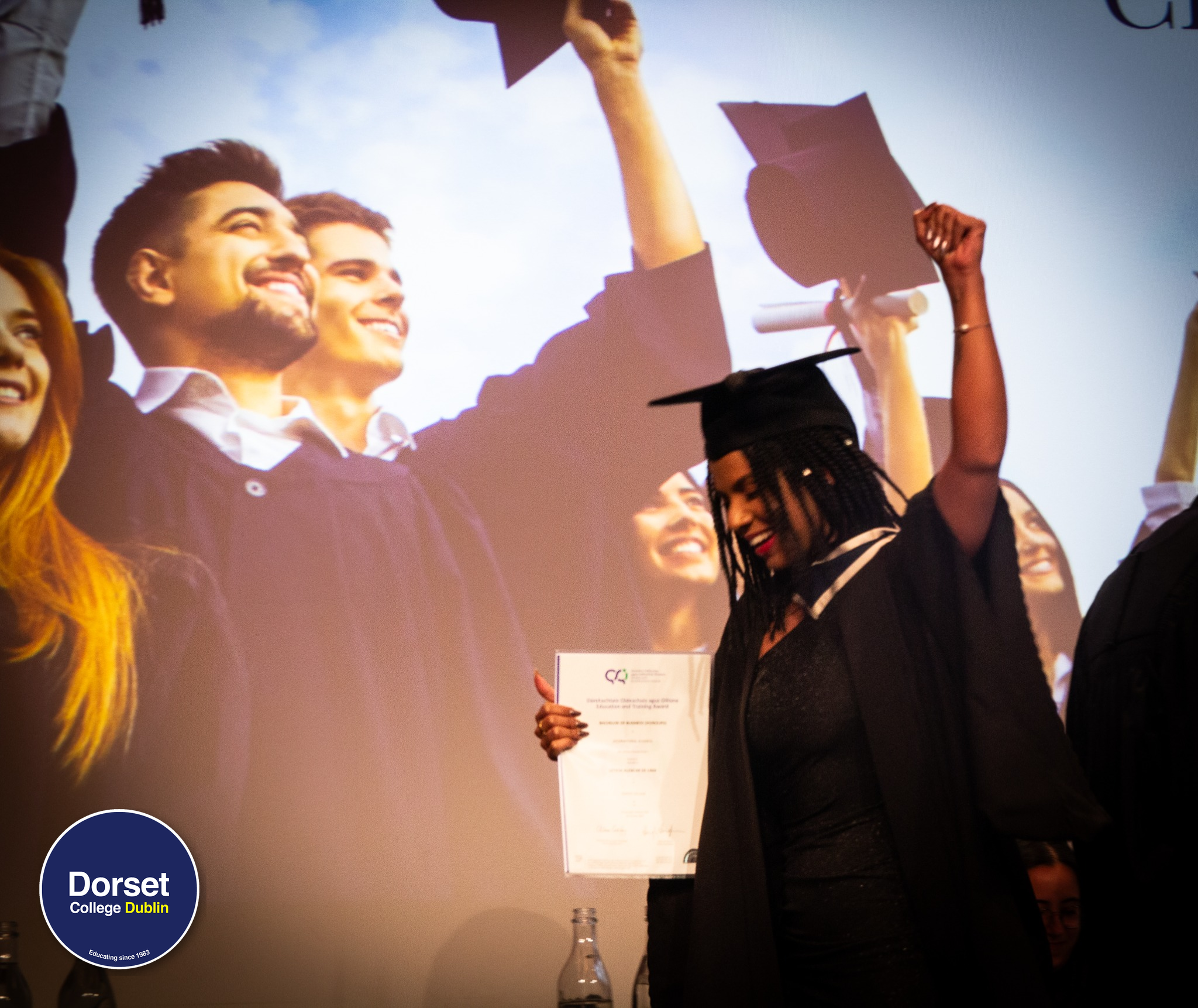 Student graduating from Dorset college, smiling and holding her QQI degree